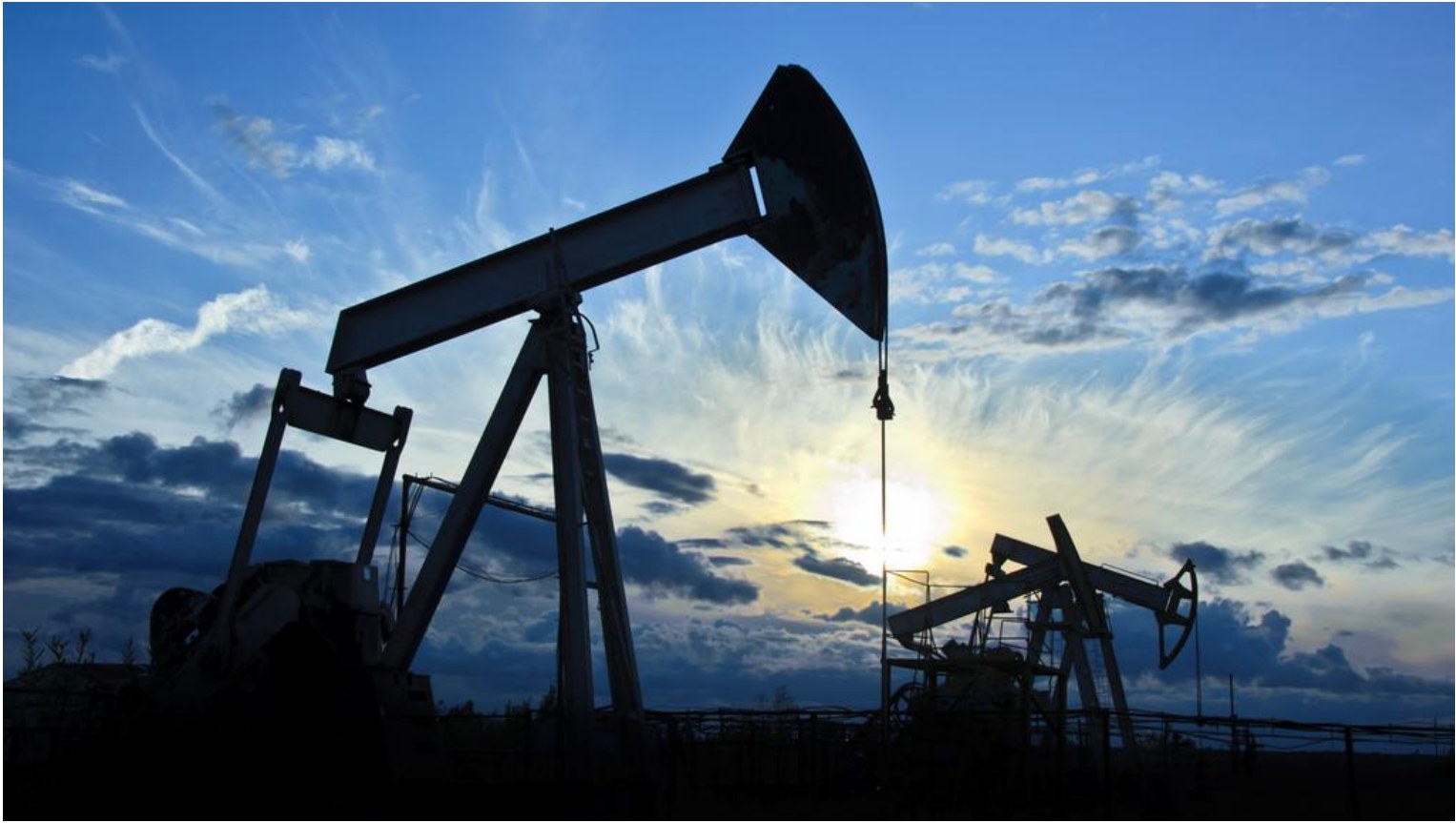 Oil pumpjacks silhouetted against an evening sky.